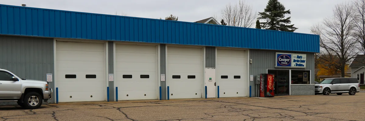 The four white overhead bay doors at Kent's Service Center under the blue roofline