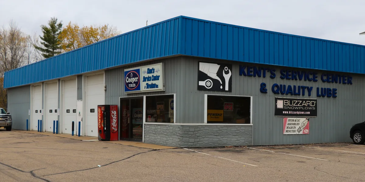 The corner building at 104 2nd St N: gray siding, blue roofline, and the wall sign reading Kent's Service Center & Quality Lube
